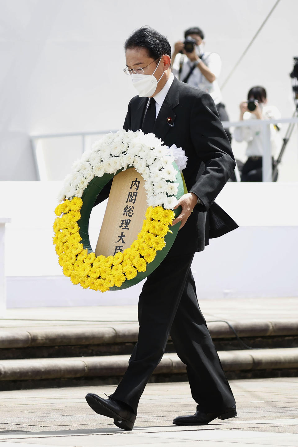 Japanese Prime Minister Fumio Kishida caries a wreath during a ceremony to mark the 77th anniversary of the atomic bombing in Nagasaki, southern Japan, Tuesday, Aug. 9, 2022. (Kyodo News via AP)