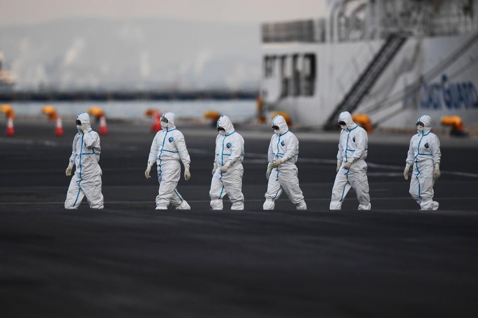 People wearing protective suits walk from the Diamond Princess cruise ship, with around 3,600 people quarantined on board due to fears of the new coronavirus, at the Daikoku Pier Cruise Terminal in Yokohama, Japan, on Feb. 10, 2020.