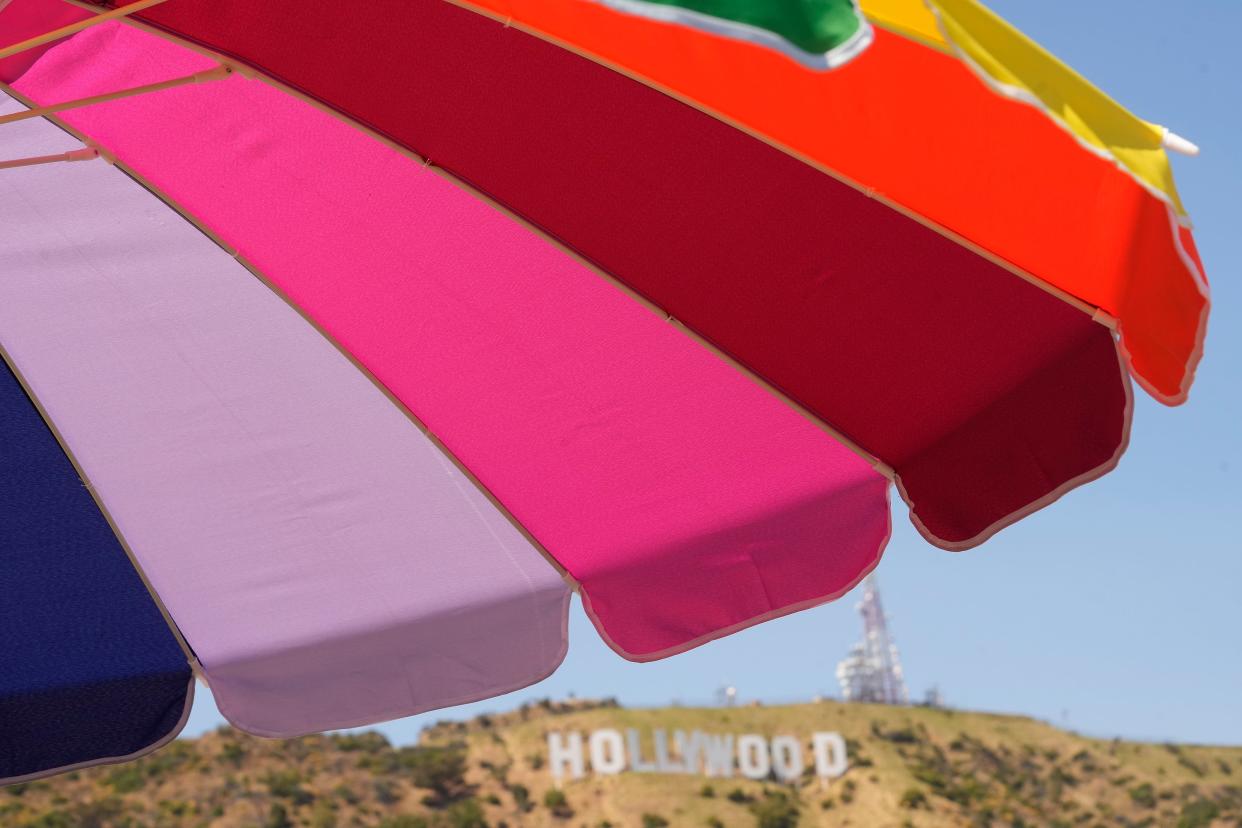 A rainbow umbrella stands with the Hollywood sign landmark seen in the background in Los Angeles (AP)