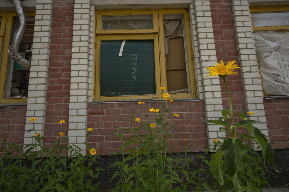Flowers grow outside a school damaged from Russian strikes, in Yahidne village, northern Chernihiv region, Ukraine, Wednesday, June 29, 2022. A few months after Russian troops retreated from Yahidne in the northern Chernihiv region, the village has gradually returned to life. No one in the village yet plans to rebuild the school; they prefer not to mention the place at all. Most of Yahidne's residents — almost 400 people — spent a month in the school's basement. (AP Photo/Nariman El-Mofty)