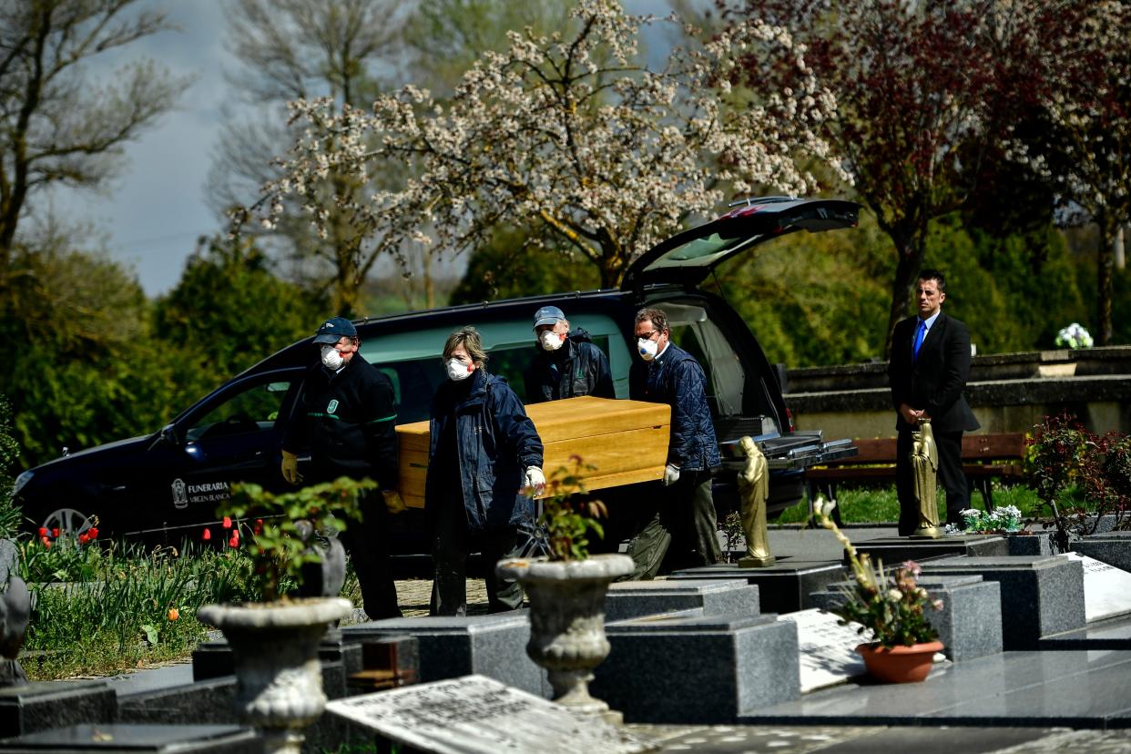 Undertakers wearing protection masks to protect from the coronavirus, carry a coffin to a burial at Salvador cemetery during the coronavirus outbreak, near to Vitoria, northern Spain,  on Monday, March 30, 2020.