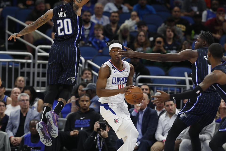 Los Angeles Clippers guard Terance Mann is defended by Orlando Magic guard Markelle Fultz (20) and center Mo Bamba (11) during the first half of an NBA basketball game Wednesday, Dec. 7, 2022, in Orlando, Fla. (AP Photo/Scott Audette)