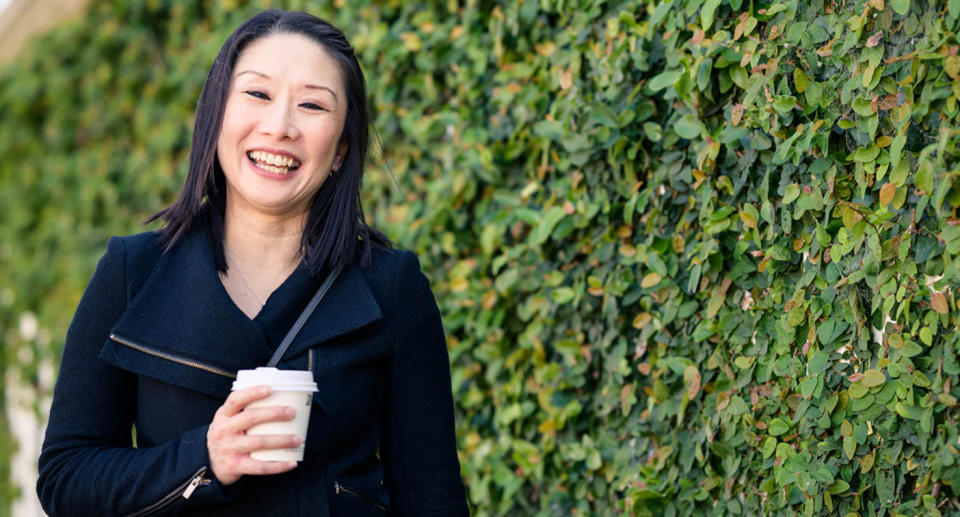 Audrey Lee stands with a coffee.