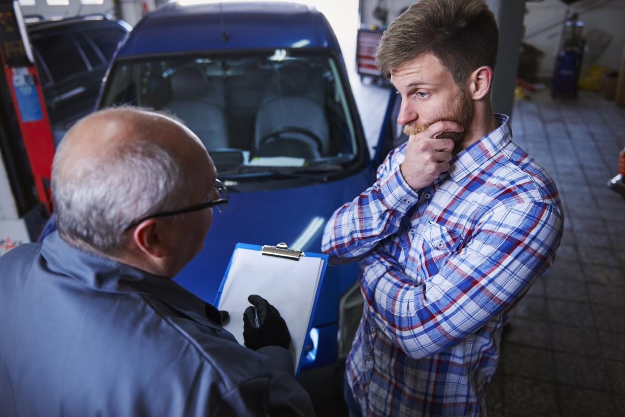 car mechanic talking to worried customer in car shop