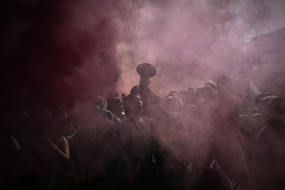 Protesters stand in the smoke of flares during a demonstration, Tuesday, Oct. 18, 2022 in Marseille, southern France. France is in the grip of transport strikes and protests for salary raise on Tuesday that threaten to dovetail with days of wage strikes that have already hobbled fuel refineries and depots, sparking chronic gasoline shortages around the country. (AP Photo/Daniel Cole)