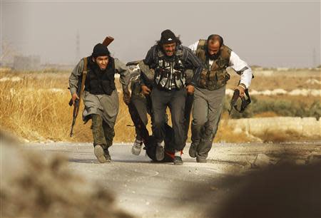 Free Syrian Army fighters drag a body of a fellow fighter after he was killed by what the FSA said was during clashes with forces loyal to Syria's President Bashar al-Assad near Base 80 near Aleppo International airport, November 8, 2013. REUTERS/Molhem Barakat