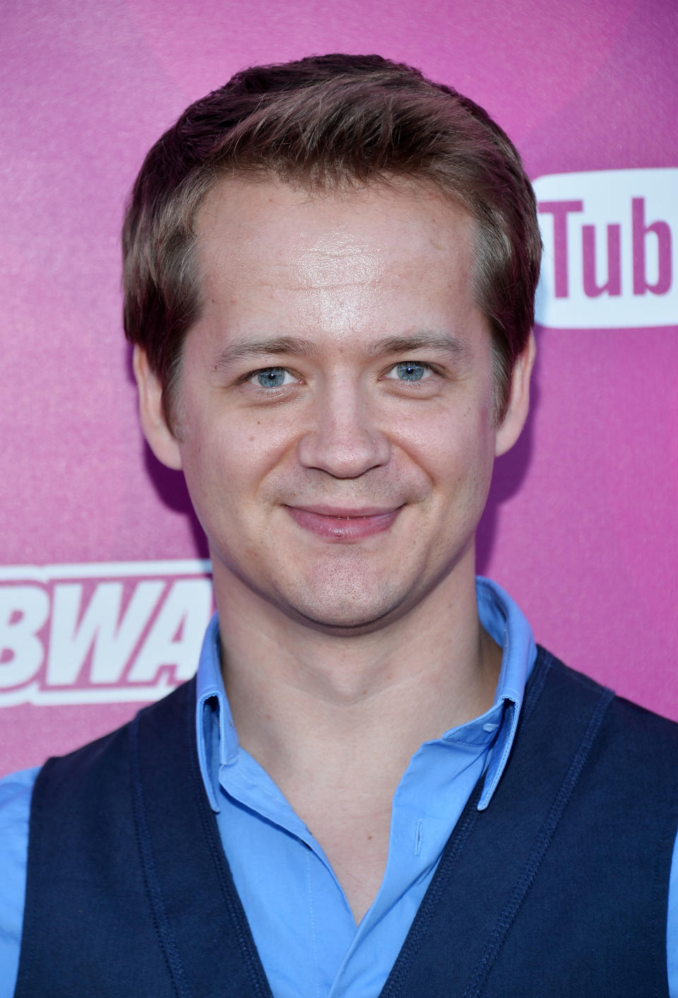 Headshot of a smiling, clean-shaven Jason in a shirt open at the top and a vest