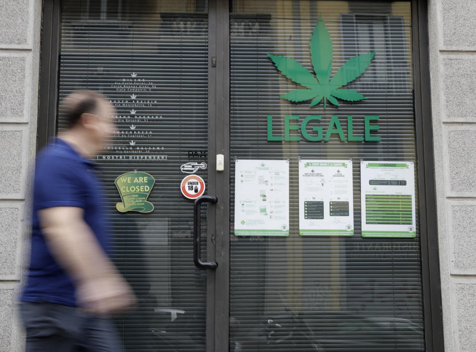 In this Thursday, June 6, 2019 photo a man walks by the entrance of a cannabis light store, in which writing reads "Legal" on the shop window, in Milan, Italy, Thursday, June 6, 2019. It’s been called Italy’s ‘’Green Gold Rush,’’ a flourishing business around light marijuana that has created 15,000 jobs and an estimated 150 million euros worth of annual revenues in under three years. But the budding sector is facing a political and judicial buzzkill. (AP Photo/Luca Bruno)