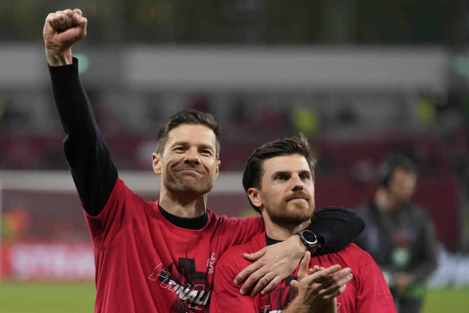 FILE - Leverkusen's head coach Xabi Alonso, left, celebrates at the end of the Europa League second leg semi-final soccer match between Leverkusen and Roma at the BayArena in Leverkusen, Germany, Thursday, May 9, 2024. A low-rise city of 167,000 that grew up around the factories of the pharmaceuticals giant Bayer, Leverkusen has little to draw tourists besides its internationally famed soccer club. The team finished an entire German Bundesliga season unbeaten Saturday and is now targeting trophies in the Europa League and German Cup. (AP Photo/Matthias Schrader, File)