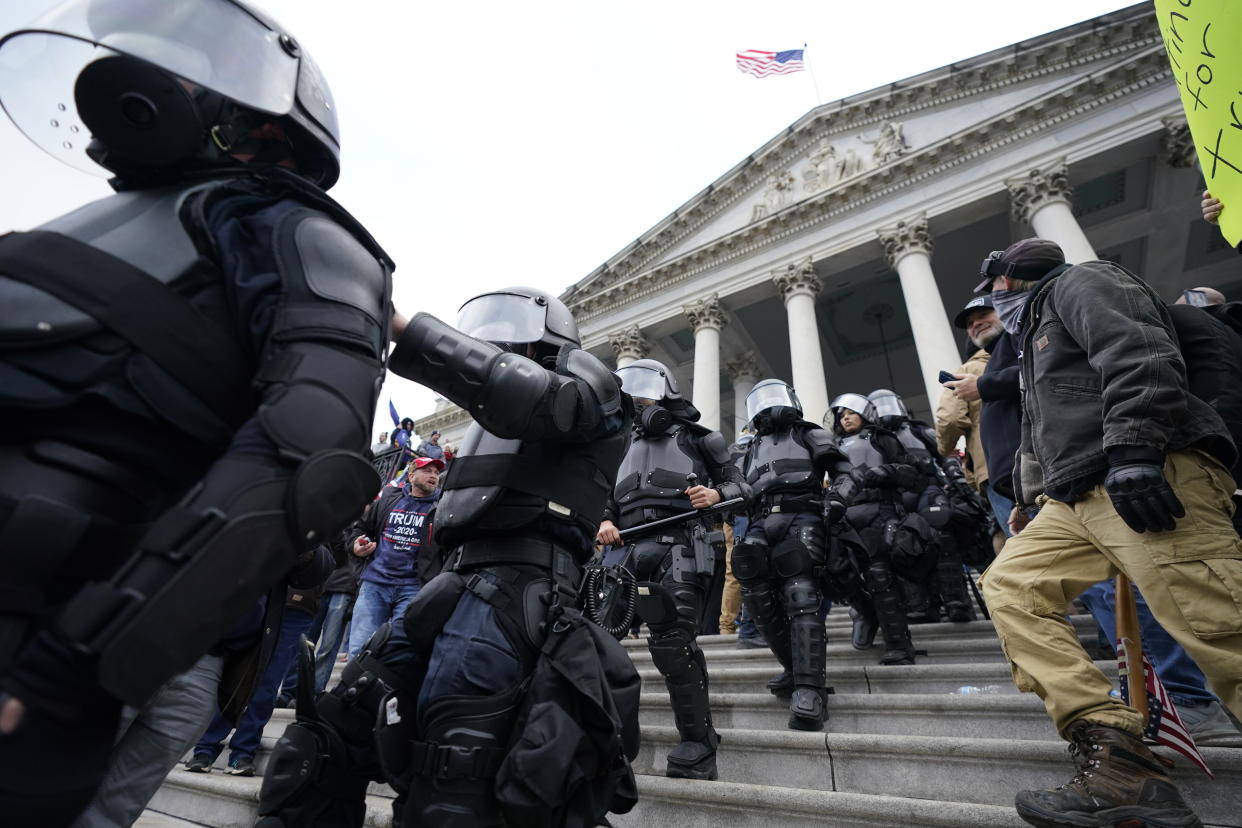 Police in riot gear walk out of the Capitol, Wednesday, Jan. 6, 2021, in Washington. As Congress prepares to affirm President-elect Joe Biden&#39;s victory, thousands of people have gathered to show their support for President Donald Trump and his claims of election fraud. (AP Photo/Manuel Balce Ceneta)