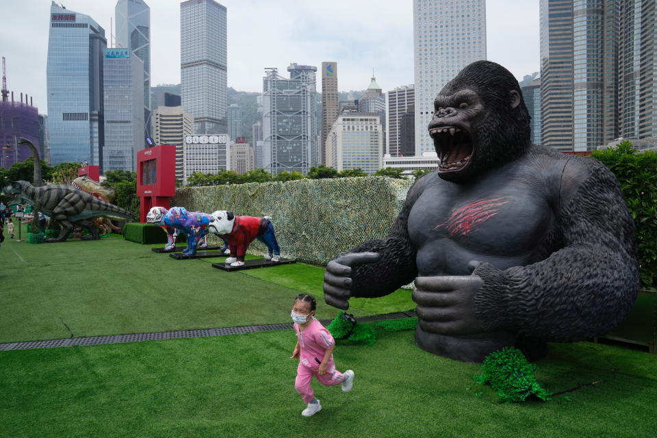 Una niña con mascarilla corre frente a una réplica de un gorila en un parque de Hong Kong el 9 de mayo de 2022. (AP Foto/Kin Cheung)