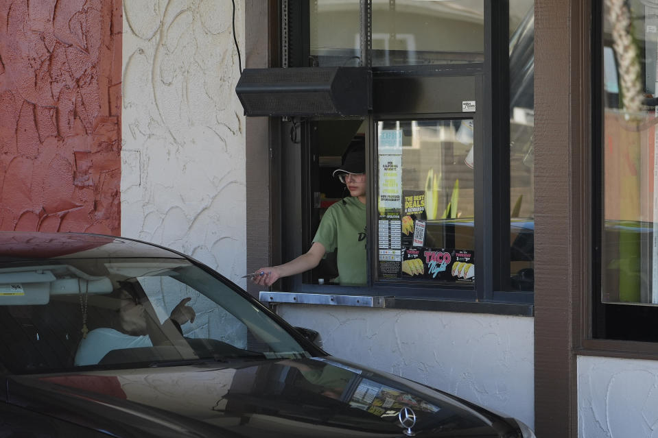 FILE - A customer pays for their food at the drive-thru of a fast-food restaurant in Los Angeles, April 1, 2024. California’s workplace regulators passed rules that would protect indoor workers from extreme heat. (AP Photo/Damian Dovarganes, File)