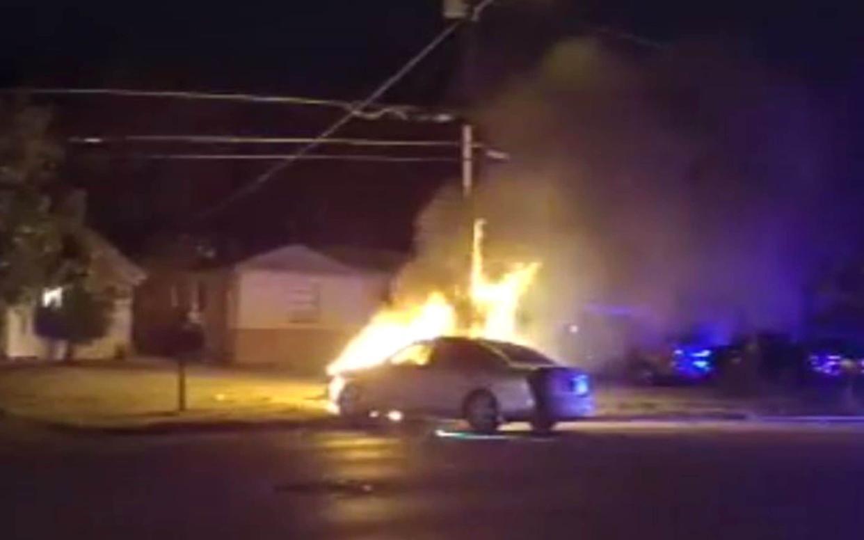 Burning car after officers dragged an unconscious woman from the car to get her away from the flames  - PA
