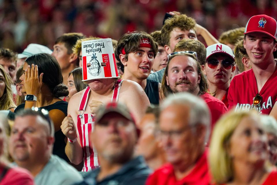 A fan with a chicken bucket on their head celebrates during a break in the third set during the match between the Nebraska Cornhuskers and the Omaha Mavericks at Memorial Stadium.