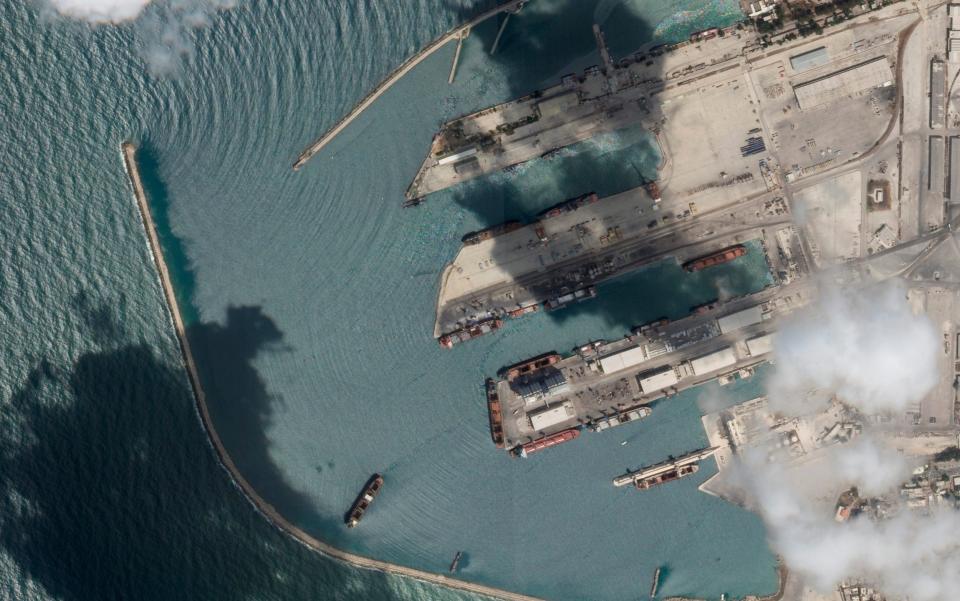 This satellite image from Planet Labs PBC shows the Sierra Leone-flagged cargo ship Razoni, centre bottom with four white cranes on its red deck, at port in Tartus, Syria - Planet Labs PBC via AP