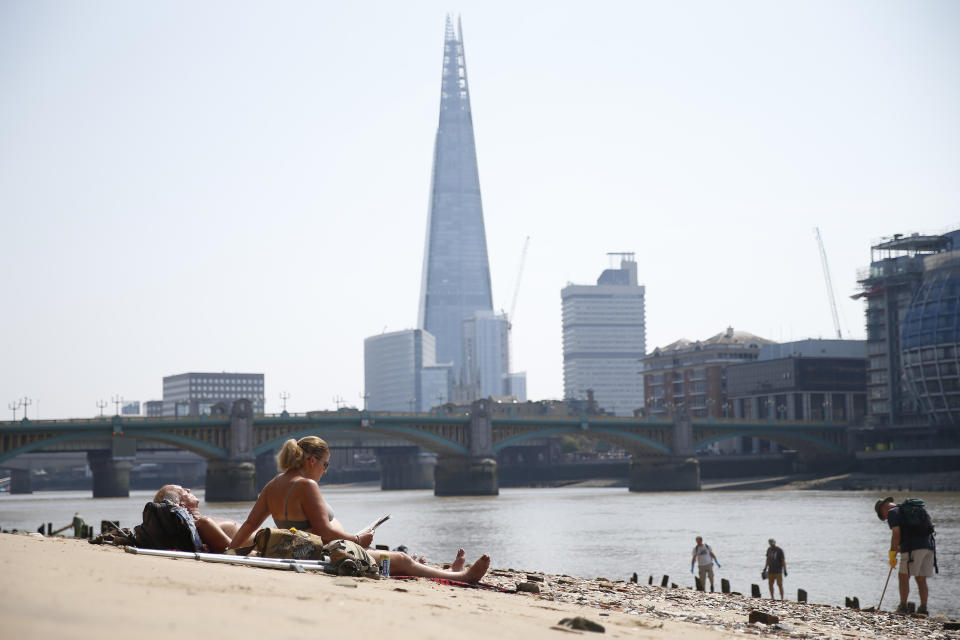 People sunbathe along the River Thames.