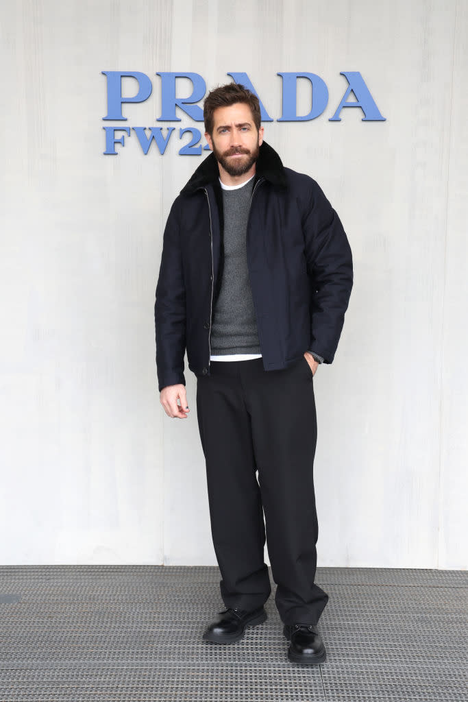 Man in a black jacket and pants with a gray sweater at the Prada FW event