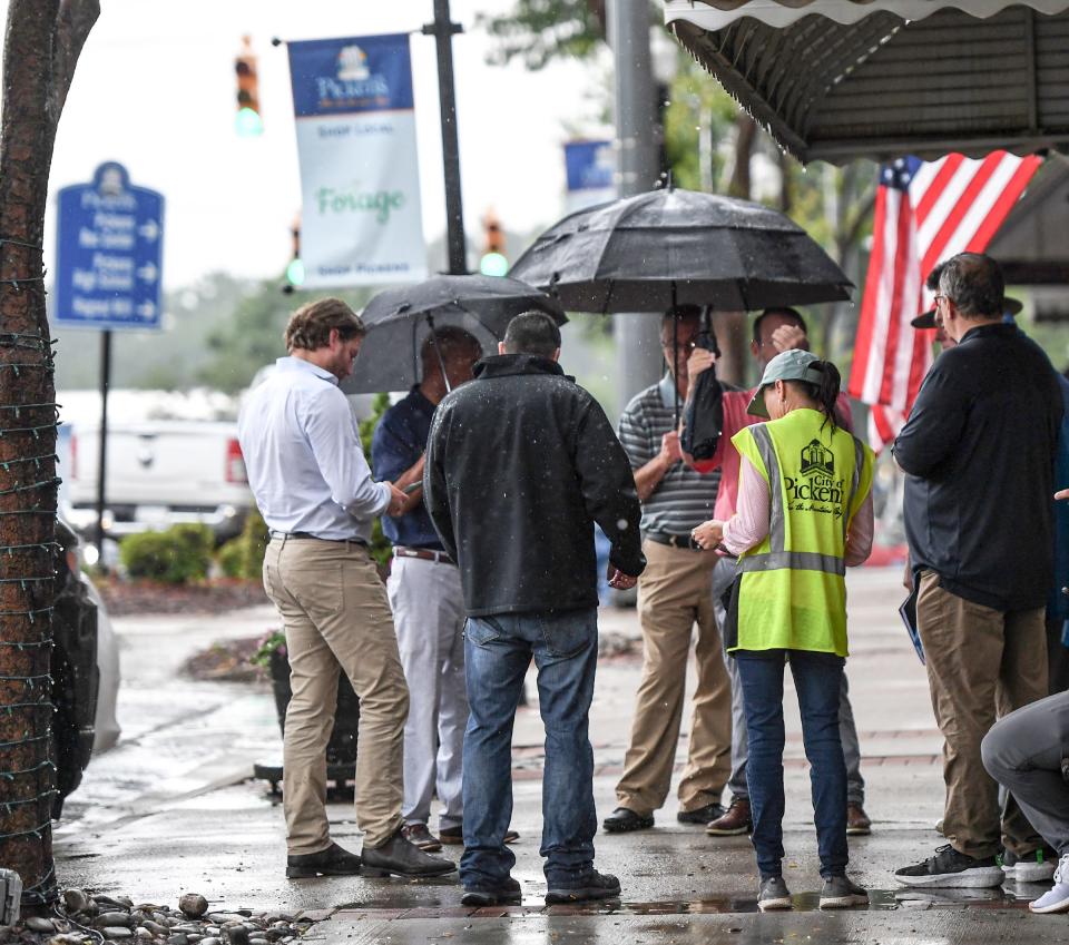 Officials gather on the sidewalk along Main Street to discuss preparations for the July 1st visit of former President Donald Trump in downtown Pickens, S.C. Tuesday, June 20, 2023. 