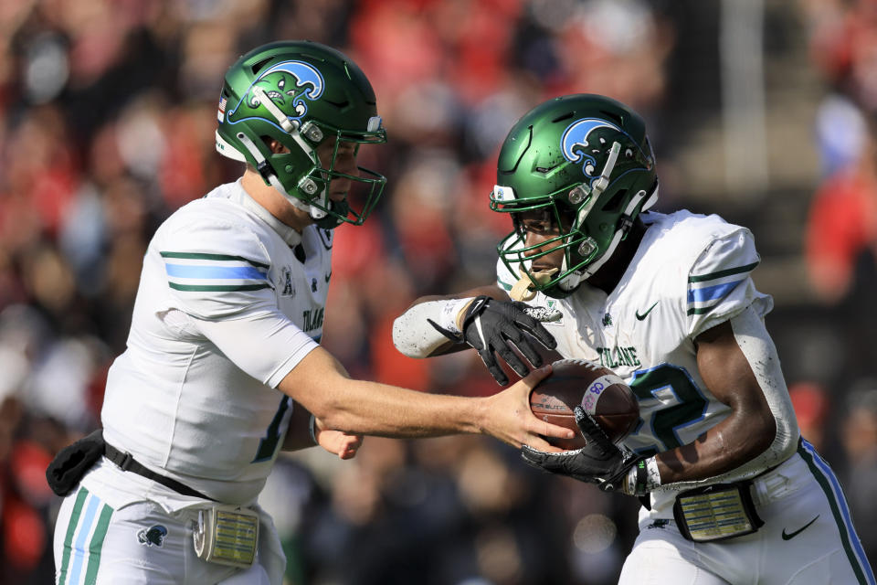 Tulane quarterback Michael Pratt, left, hands the ball off to running back Tyjae Spears during the first half of an NCAA college football game against Cincinnati, Friday, Nov. 25, 2022, in Cincinnati. (AP Photo/Aaron Doster)
