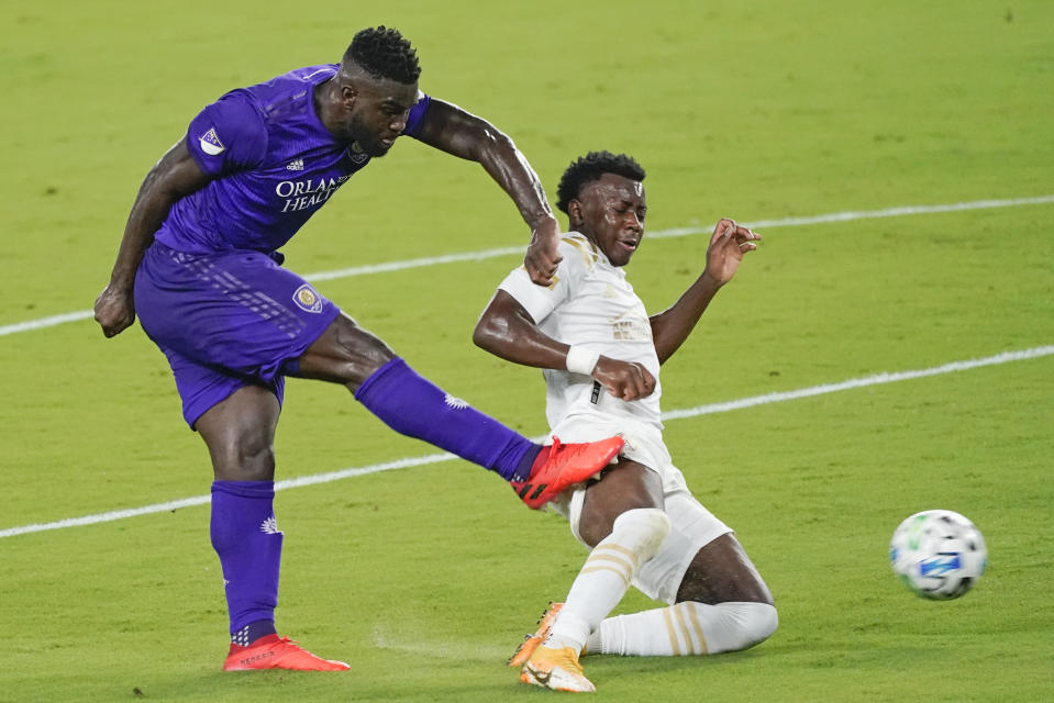 Orlando City forward Daryl Dike, left, takes a shot on goal past Atlanta United defender George Bello during the first half of an MLS soccer match Wednesday, Oct. 28, 2020, in Orlando, Fla. (AP Photo/John Raoux)