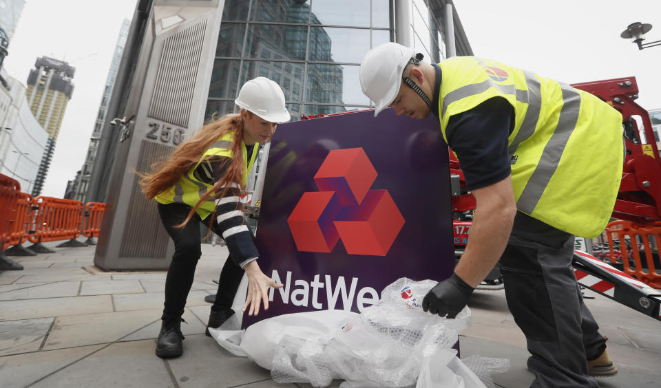 Workers unwrap a NatWest Bank sign before it is erected at 250 Bishopsgate in London