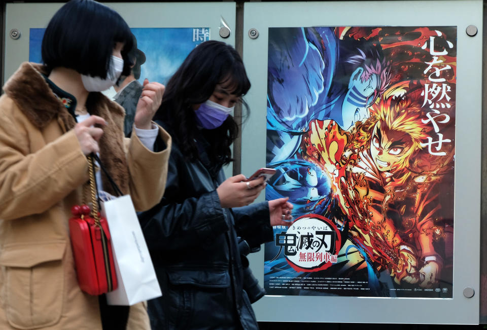 En esta imagen tomada el 16 de diciembre de 2020, los peatones pasan junto a un cartel que promociona la película de anime Demon Slayer - Kimetsu no Yaiba the Movie: Mugen Train - en un cine en Tokio. (Foto de KAZUHIRO NOGI / AFP a través de Getty Images)