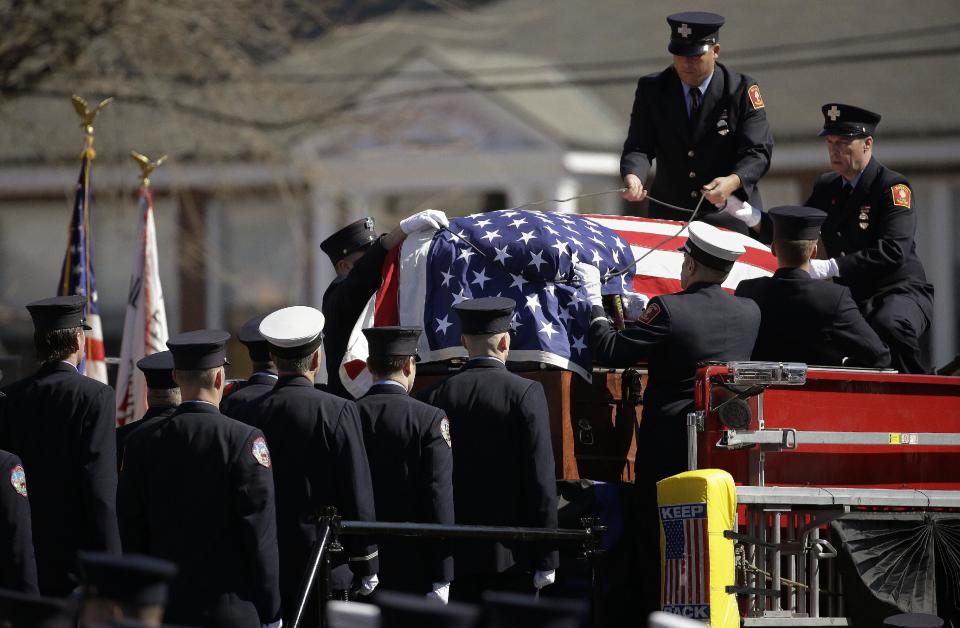 The casket containing the body of Boston firefighter Michael R. Kennedy is unlashed from his fire truck after arriving at Holy Name Church for his funeral in Boston, Thursday, April 3, 2014. Kennedy and Boston Fire Lt. Edward J. Walsh were killed Wednesday, March 26, 2014 when they were trapped in the basement of a burning brownstone during a nine-alarm blaze.(AP Photo/Stephan Savoia)