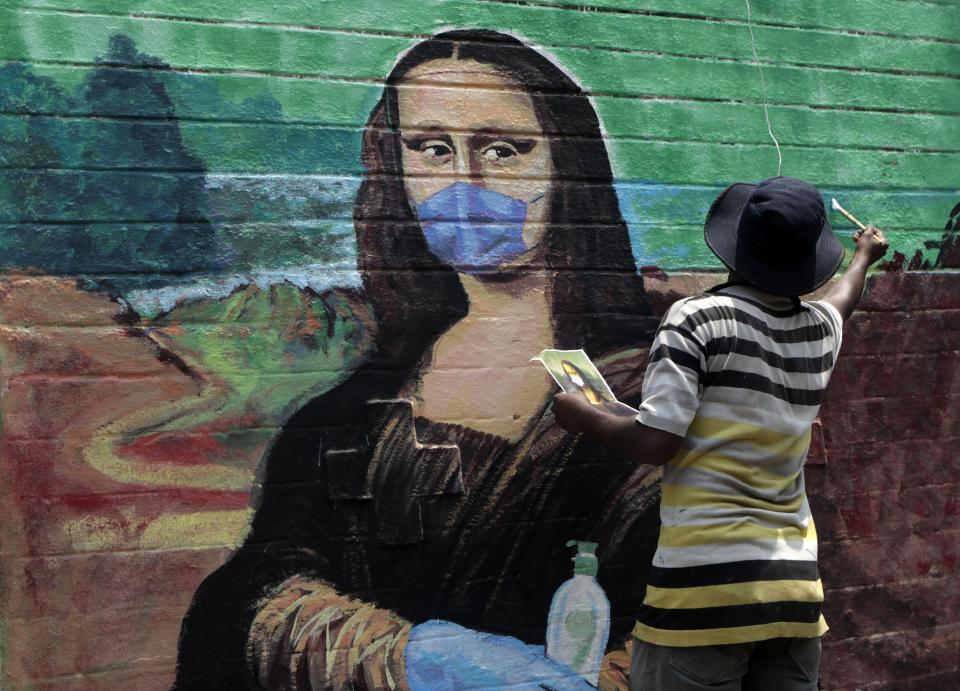 An artist makes a mural of the Monalisa wearing a face mask to spread awareness for the prevention of the coronavirus in Mumbai, India, Wednesday, March 24, 2021. (AP Photo/Rajanish Kakade)