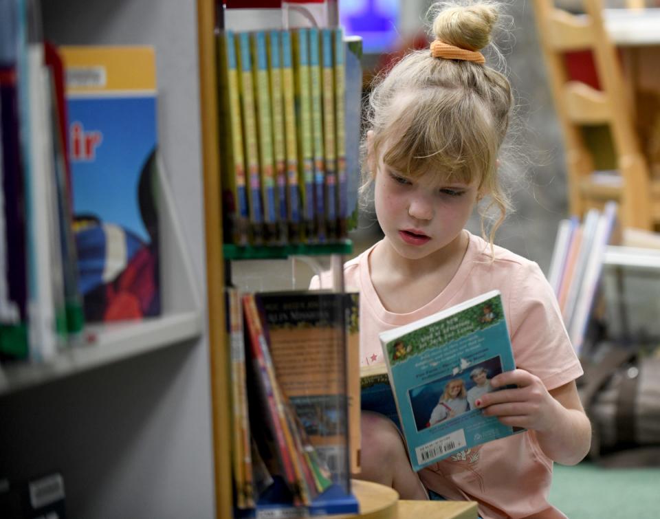 Gloria Zimmerman, 6, of Navarre picks a chapter book from the shelves Monday, April 1, 2024, at Massillon Public Library on a rainy day.
