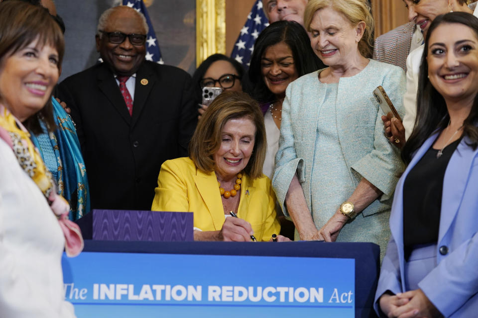 FILE - House Speaker Nancy Pelosi of Calif., surrounded by House Democrats, signs the Inflation Reduction Act of 2022 during a bill enrollment ceremony on Capitol Hill in Washington, Aug. 12, 2022. The one-year anniversary of the Inflation Reduction Act being signed into law is on Wednesday, Aug. 16, 2023. (AP Photo/Mariam Zuhaib, File)