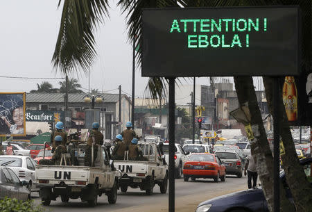 A U.N. convoy of soldiers passes a screen displaying a message on Ebola on a street in Abidjan August 14, 2014. REUTERS/Luc Gnago