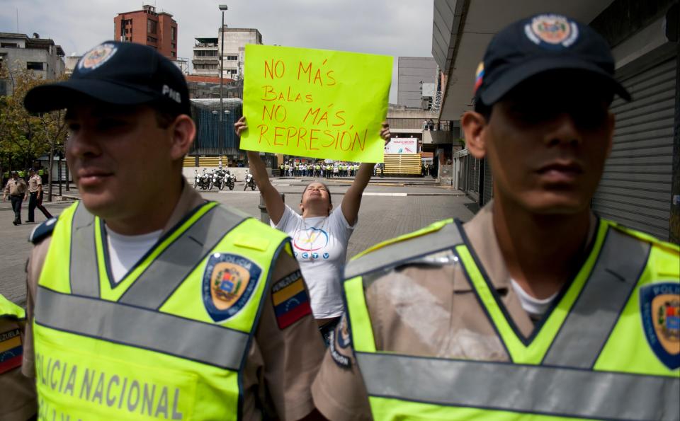 An anti-government demonstrator holds up a poster that reads in Spanish; "No more bullets, no more repression," during a protest in Caracas, Venezuela, Tuesday, Feb 18, 2014. Fears of more clashes between pro- and anti-government supporters ratcheted up in Venezuela as both sides held demonstrations in the capital Tuesday and opposition leader Leonardo Lopez dared authorities to arrest him. (AP Photo/Juan Manuel Hernandez)