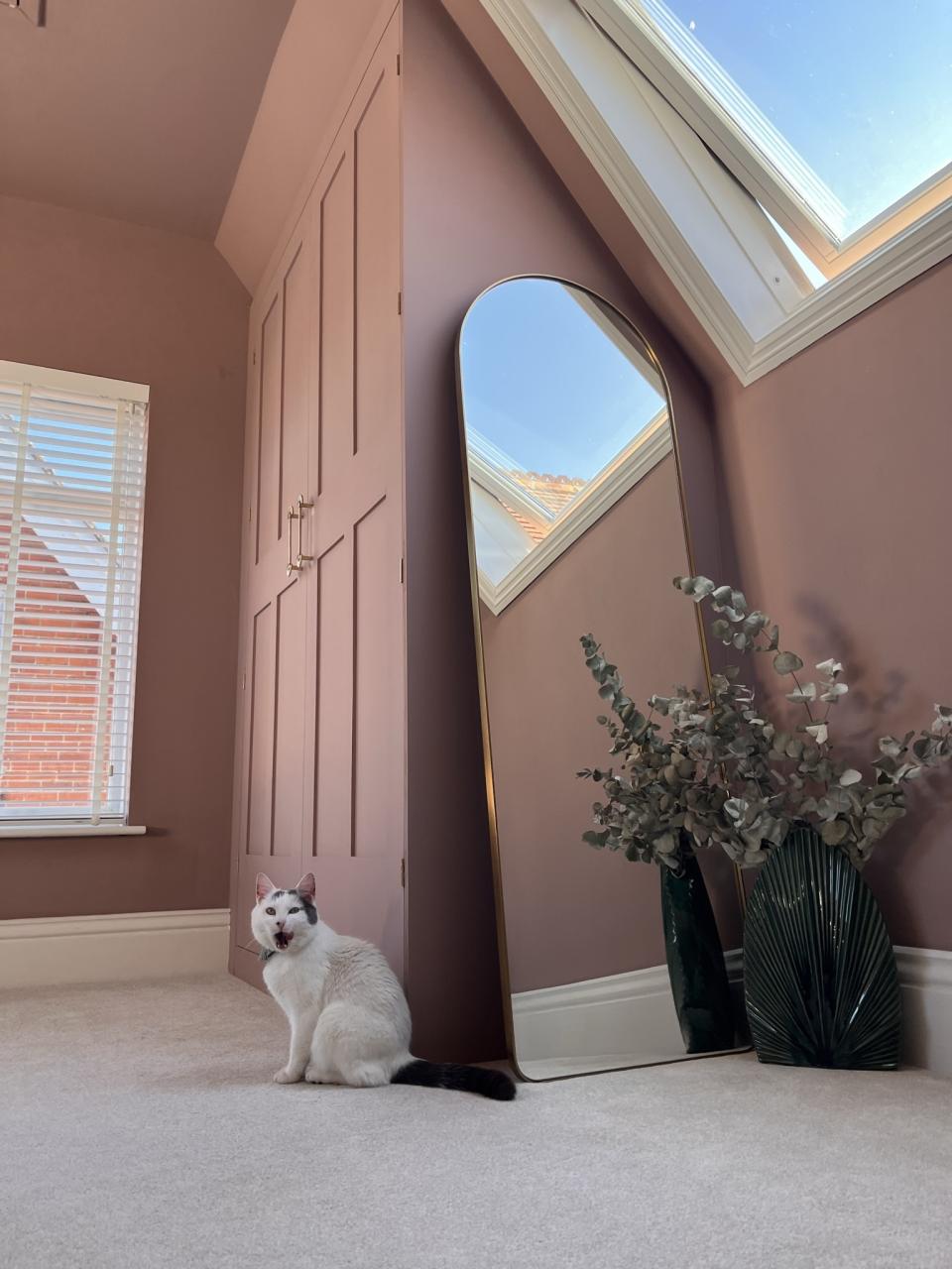 An attic room painted purple with a pitched ceiling and a built-in IKEA pax wardrobe in the corner