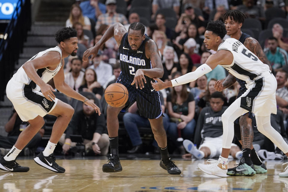 Orlando Magic's Al-Farouq Aminu (2) chases the ball against San Antonio Spurs' Dejounte Murray (5) and Dedric Lawson during the first half of an NBA preseason basketball game, Saturday, Oct. 5, 2019, in San Antonio. (AP Photo/Darren Abate)