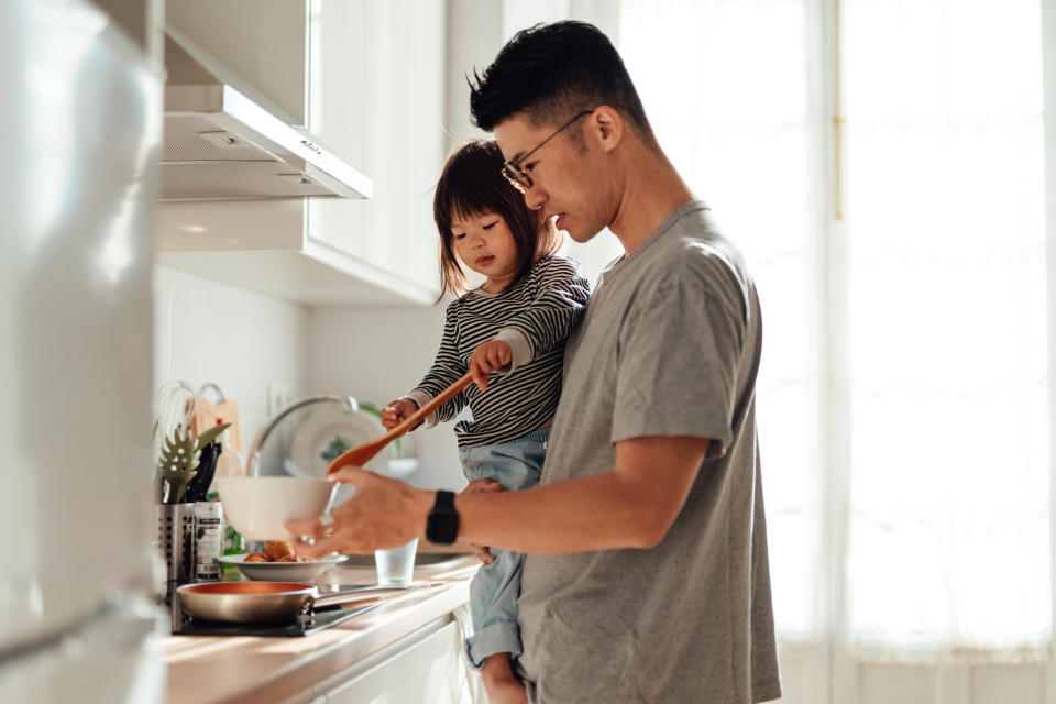 Asian stay-at-home dad teaching his little daughter cooking in kitchen at home. Modern manhood and fatherhood. Healthy family lifestyle.