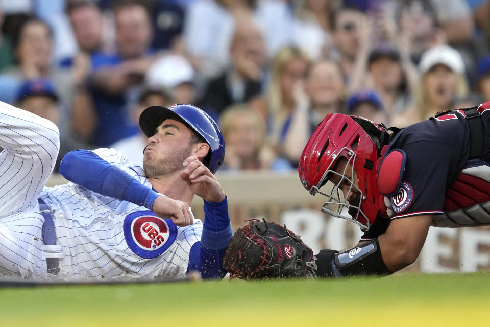 Chicago Cubs' Cody Bellinger, left, scores past Washington Nationals catcher Keibert Ruiz, off Christopher Morel's single during the second inning of a baseball game Monday, July 17, 2023, in Chicago. (AP Photo/Charles Rex Arbogast)