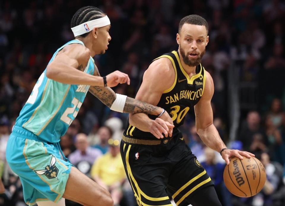Golden State Warriors guard Steph Curry, right, begins to drive around Charlotte Hornets guard Tre Mann, left, during first quarter action at Spectrum Center in Charlotte, NC on Friday, March 29, 2024. JEFF SINER/jsiner@charlotteobserver.com