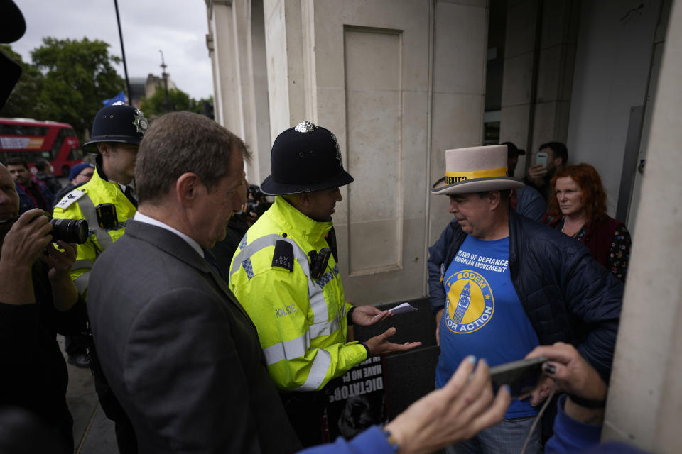 FILE-A police officer speaks to anti-Brexit protester Steve Bray, with Bray supporter Alastair Campbell, the press officer to former British Prime Minister Tony Blair, at left, near the Houses of Parliament, in London, Wednesday, June 29, 2022. Britain is one of the world's oldest democracies, but some worry that essential rights and freedoms are under threat. They point to restrictions on protest imposed by the Conservative government that have seen environmental activists jailed for peaceful but disruptive actions. (AP Photo/Matt Dunham, File)