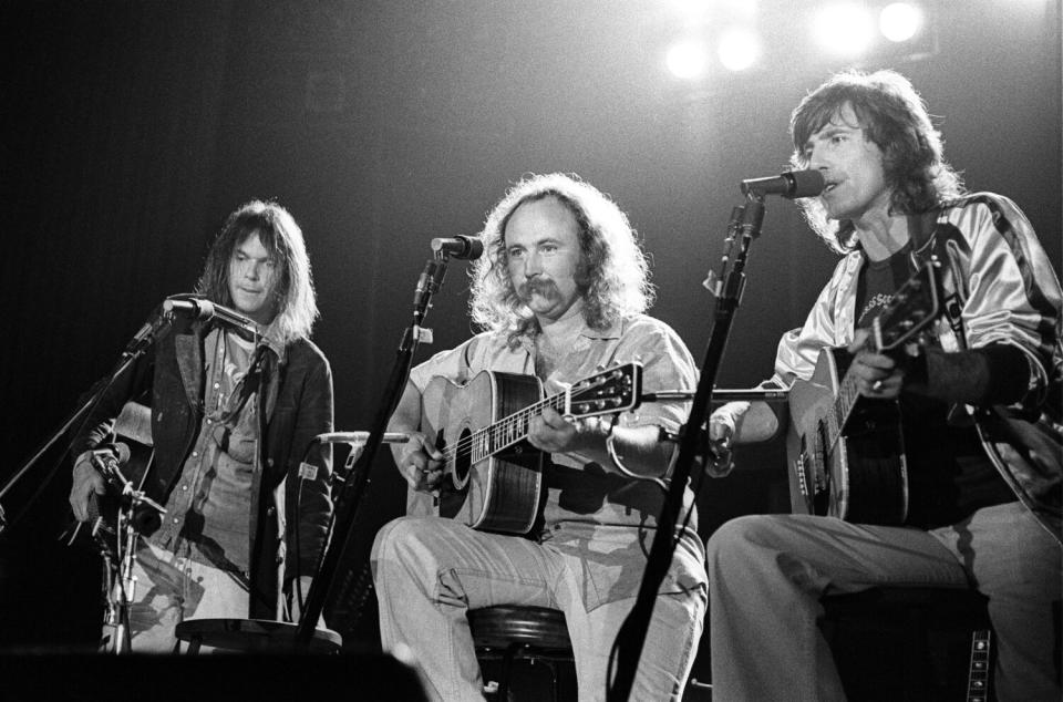 Three men with acoustic guitars perform onstage
