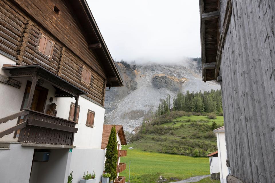 rocks are seen on a mountainside between houses in Brienz-Brinzauls, Switzerland