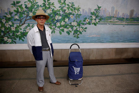 A man wearing sunglasses stands next to his shopping bag and waits for a train at a subway station visited by foreign reporters on a government organised tour in central Pyongyang, North Korea May 7, 2016. REUTERS/Damir Sagolj/File photo