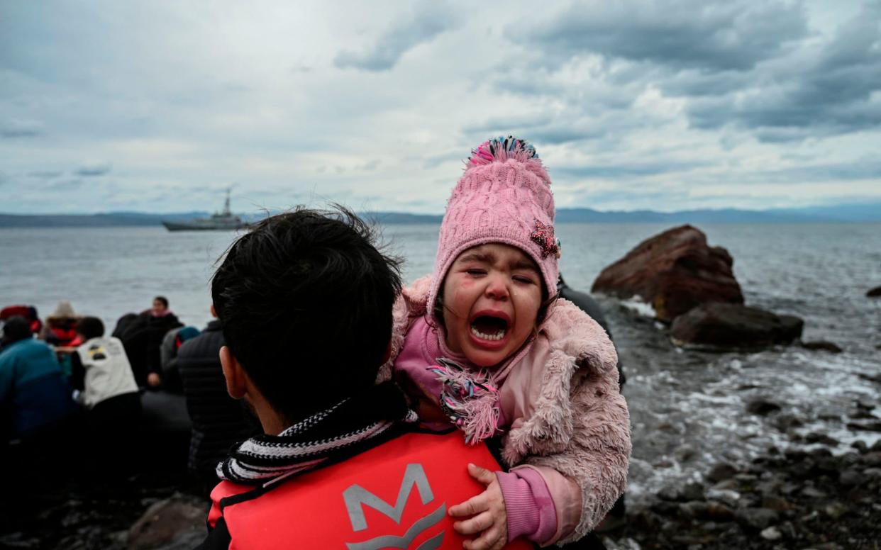 A child cries as a dinghy with 54 Afghan refugees lands ashore the Greek island of Lesbos - AFP