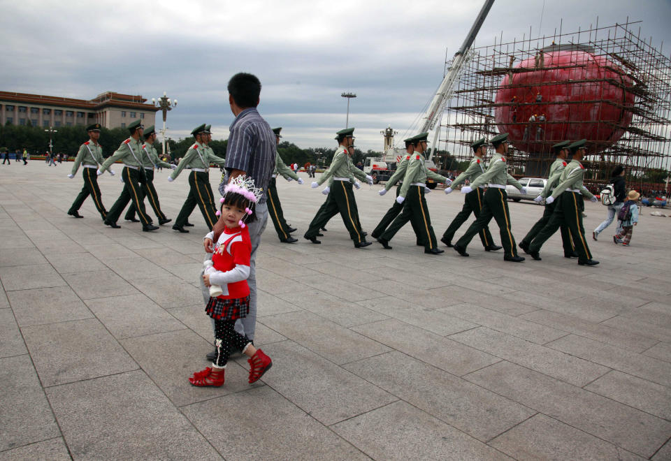 FILE - In this file photo taken Friday, Sept. 16, 2011, a Chinese girl in ethnic minority costume walks past Chinese paramilitary police marching across Tiananmen Square near the Great Hall of the People where the annual National People's Congress is held in March in Beijing, China. A glance at history suggests it's easier for a Chinese woman to orbit Earth than to land a spot on the highest rung of Chinese politics. In June, the 33-year-old Air Force major marked a major feminist milestone by becoming the first Chinese woman to travel in space. With a once-a-decade leadership transition set to kick off Nov. 8, many now are waiting to see if another ambitious Chinese female, State Councilor Liu Yandong, can win one of the nine spots at the apex of Chinese power. (AP Photo/Ng Han Guan, File)