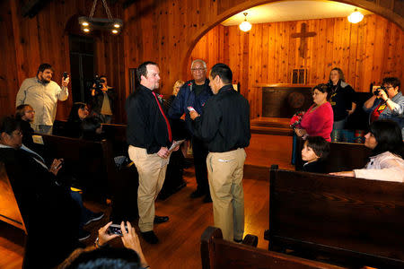 FILE PHOTO: Darren Black Bear (R) reads his vows from his cellphone to Jason Pickel (L) as they are married by Darren's father Rev. Floyd Black Bear (C) in El Reno, Oklahoma October 31, 2013. REUTERS/Rick Wilking/File Photo