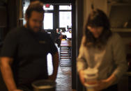 Empty stools stand in the background as James Mark, left, owner of the restaurant Big King, talks with Jennifer Wittlin as they prepare for dinner takeout orders Wednesday, March 25, 2020, in Providence, R.I. Mark said pushing to restart the economy before the health crisis is over would put businesses like his in a terrible position. As things are now, there's some leverage for small businesses to negotiate with landlords or banks over rents, mortgages and debt payments. "I don't think there's any economic solution until the health side of this gets solved," Mark said. "We can't rush this." (AP Photo/David Goldman)