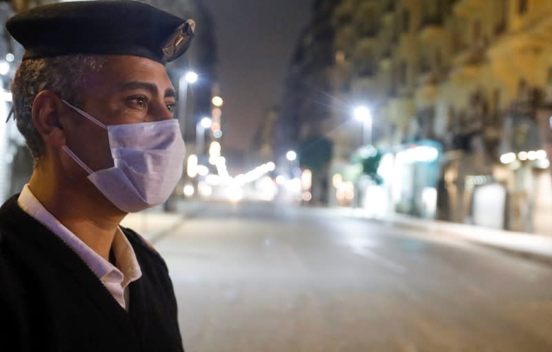 A police officer stands at the Qasr El Nil street during the first day of a two-weeks night-time curfew which was ordered by the Egyptian Prime Minister Mostafa Madbouly to contain the spread of the coronavirus disease (COVID-19), in Cairo