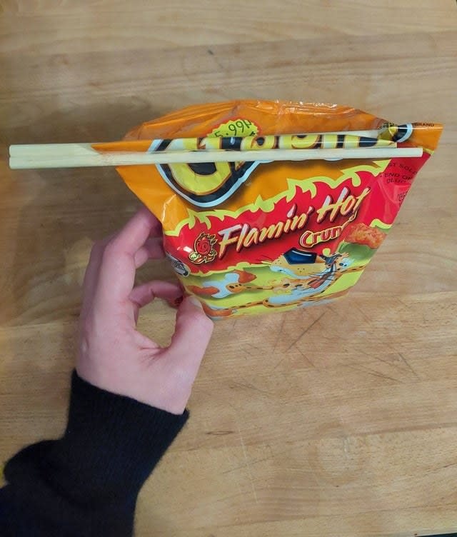 A bag of Cheeto's closed with a pair of chopsticks.