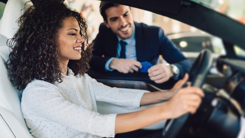 Smiling woman in the showroom enjoying luxury car.