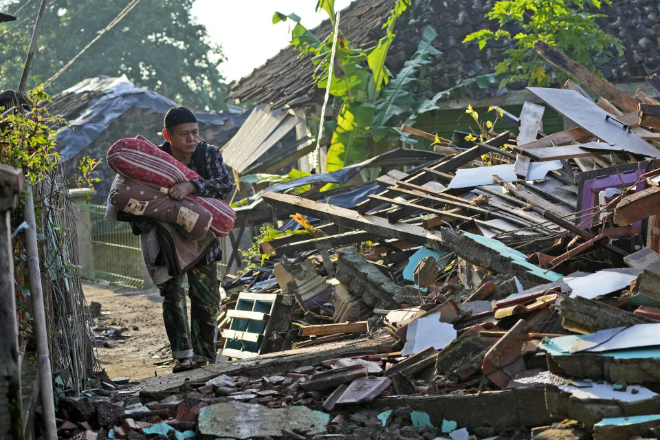 A man carries his belongings as he walks through a destroyed neighborhood from Monday's earthquake in Cianjur, West Java, Indonesia, Thursday, Nov. 24, 2022. The 5.6 magnitude earthquake left hundreds dead, injures and missing as buildings crumbled and terrified residents ran for their lives on Indonesia's main island of Java. (AP Photo/Tatan Syuflana)