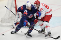 Unted States' Jake Sanderson, left, challenges for a puck with Poland's Patryk Krezolek during the preliminary round match between Poland and United States at the Ice Hockey World Championships in Ostrava, Czech Republic, Friday, May 17, 2024. (AP Photo/Darko Vojinovic)